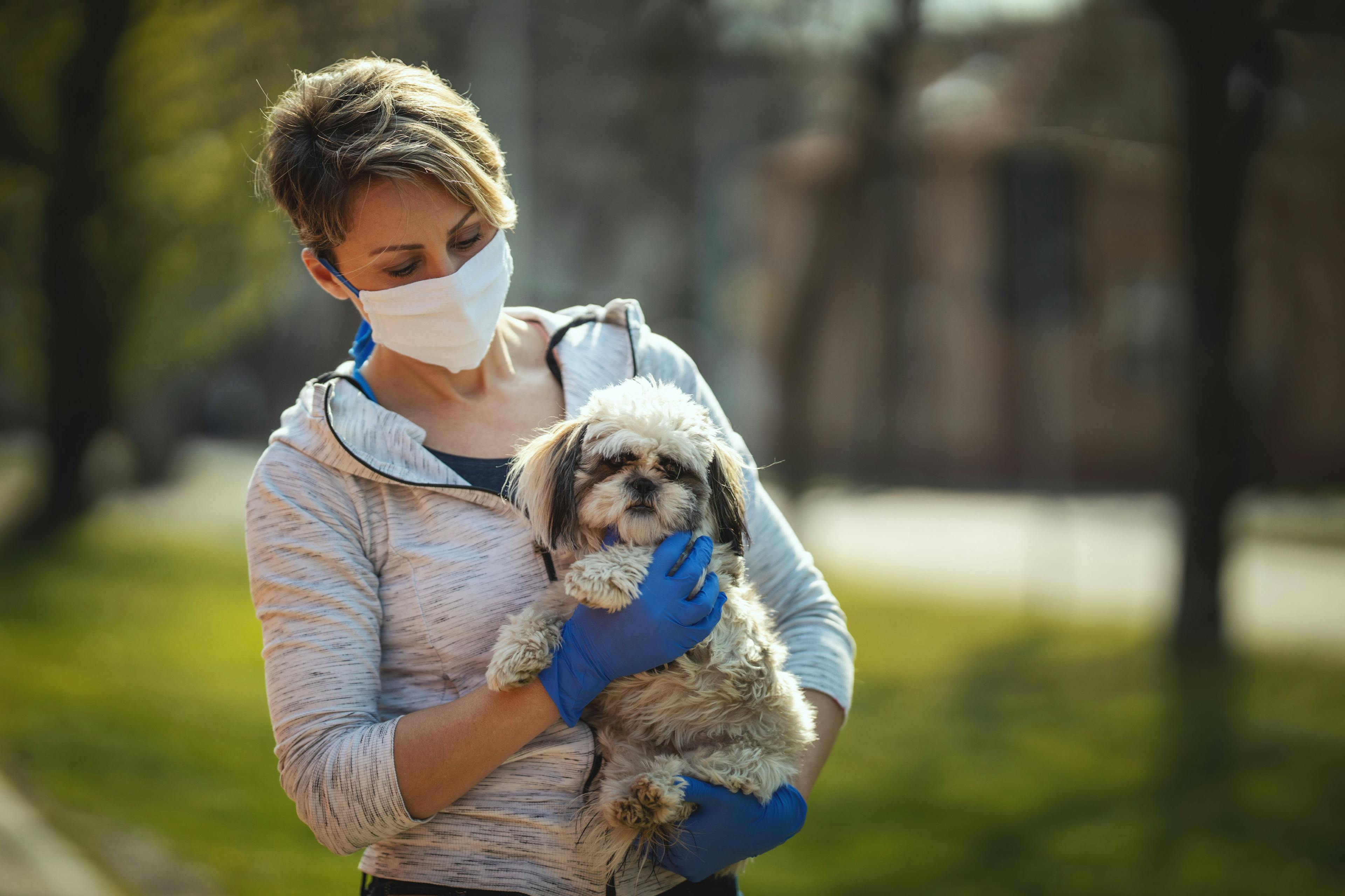 pet owner wearing mask and holding dog