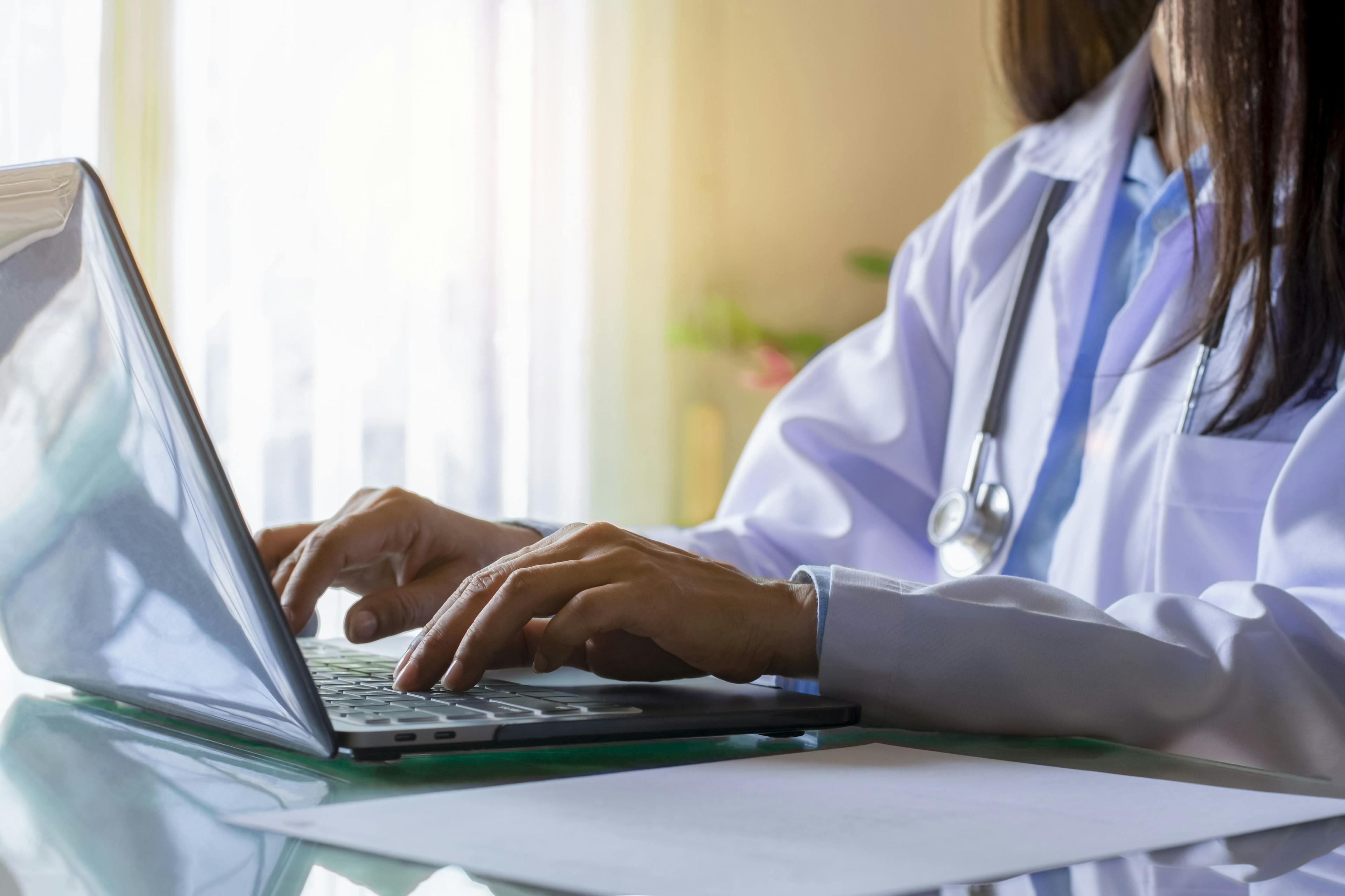 Woman doctor typing on laptop for telehealth