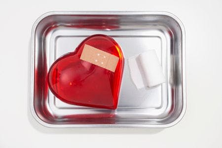 veterinary-still-life-of-red-heart-covered-with-band-aid-in-silver-bowl-78233733-body-1.jpg
