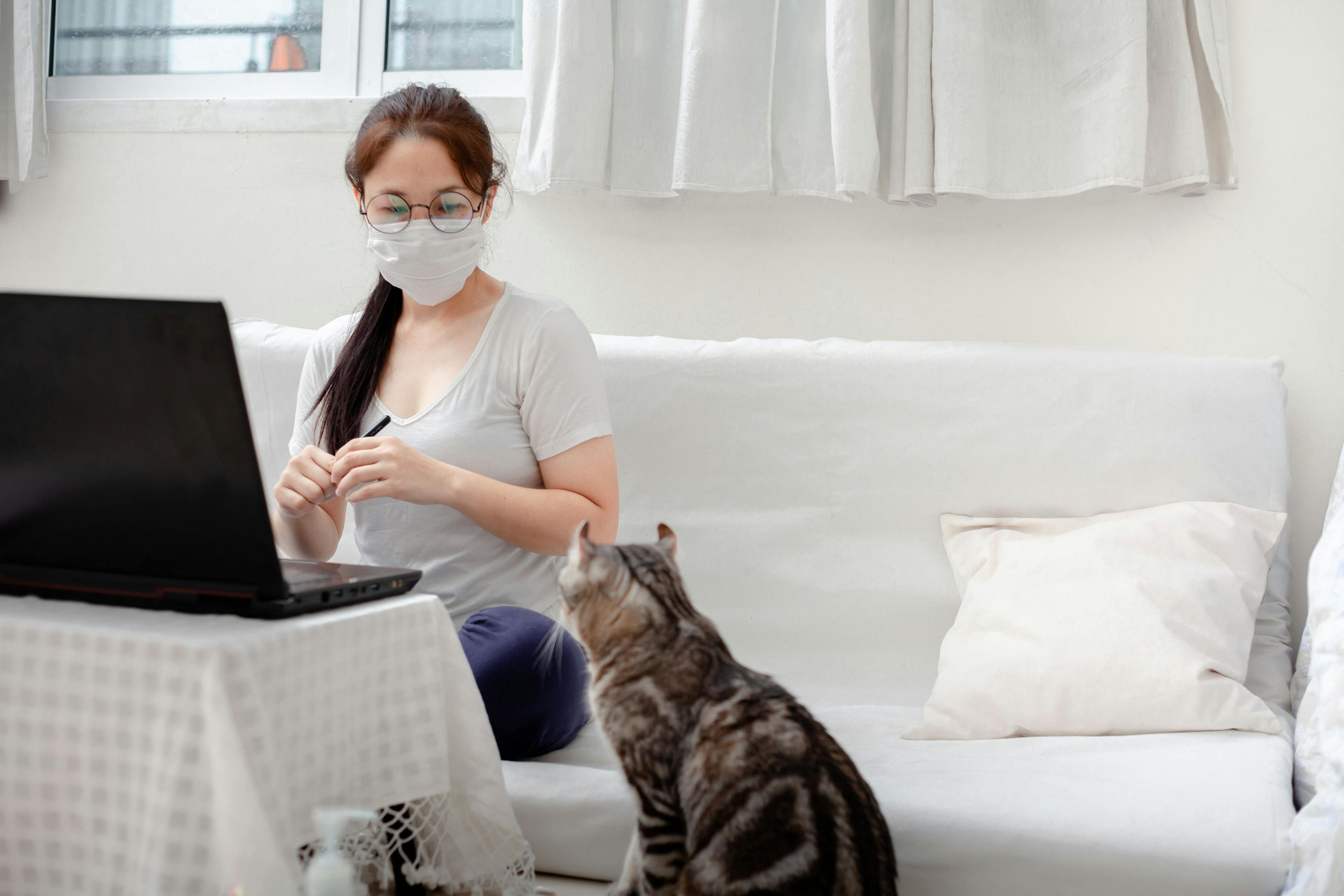woman with mask looking at cat