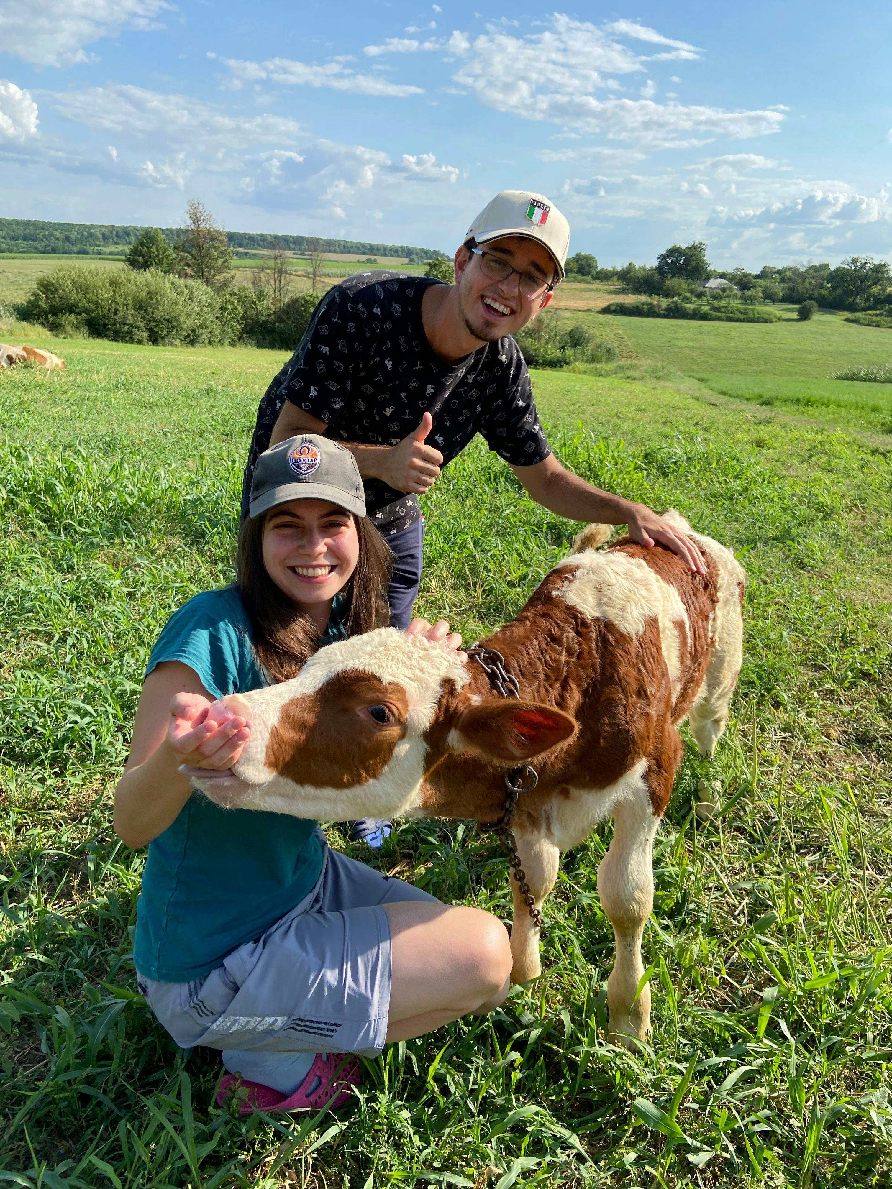 Maryna Mullerman and her boyfriend, Vlad Pinkhasov, make friends with a calf in the countryside outside of Kharkiv, Ukraine, in August 2021.