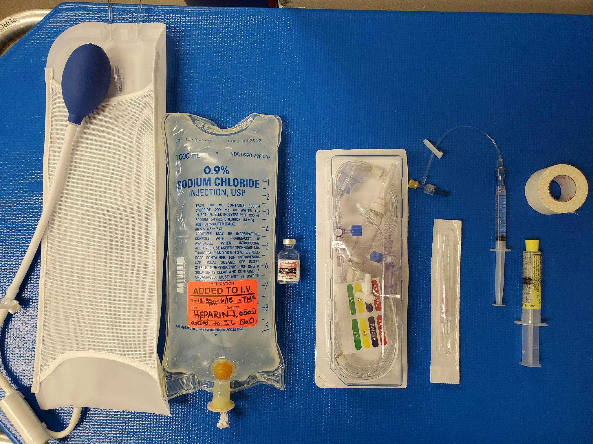 Figure 1. Basic setup for placement and monitoring of arterial blood pressure. From left to right: pressure bag for sodium chloride (NaCl), heparinized NaCl bag, heparin 1000 U/mL, fluid bag spike and transducer appropriate for your multiparameter monitor, appropriate-sized catheter, T set flushed with heparinized saline, extra heparinized saline flush, medical tape to secure catheter.